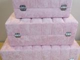 three pink boxes stacked on top of each other on a wooden floor