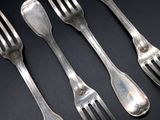 four forks and two spoons on a black table