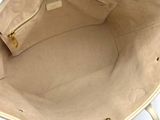 someone is holding a beige purse with gold handles on a white table