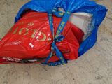un sac rouge muni d'une poignée bleue posé par terre