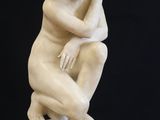 statue of a woman sitting on top of a white pedestal