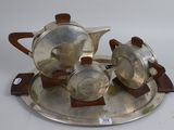 a silver tea set on a silver tray on a white surface
