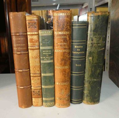 plusieurs vieux livres sont alignés sur une étagère dans une bibliothèque