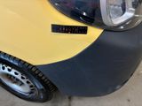 a small yellow car with a sticker on the front of it