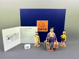 three figurines of a man sitting on a chair next to a card