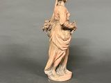 an old statue of a woman holding a basket of flowers
