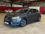 La voiture grise est garée dans un garage avec d'autres voitures.