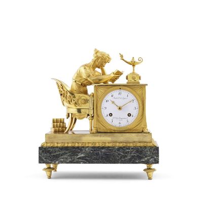 une horloge en or sur laquelle figure un homme en train de lire un livre