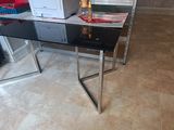 une table en verre sur laquelle se trouve un ordinateur, dans une pièce