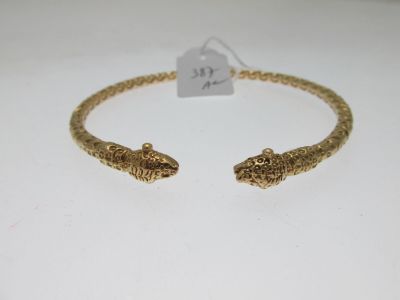 a close up of a gold bracelet with two snakes on it