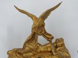 a gold statue of a woman and a bird on top of a clock
