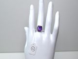 la main de quelqu'un tenant une bague sertie d'une pierre violette