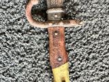 a close up of a knife with a yellow handle on a carpet