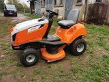 an orange ride on lawn mower parked in front of a house