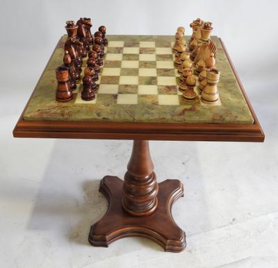 un jeu d'échecs ancien posé sur un socle surmonté d'un plateau en marbre