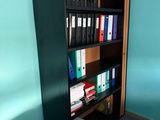a black bookcase with many files on it in the corner of a room