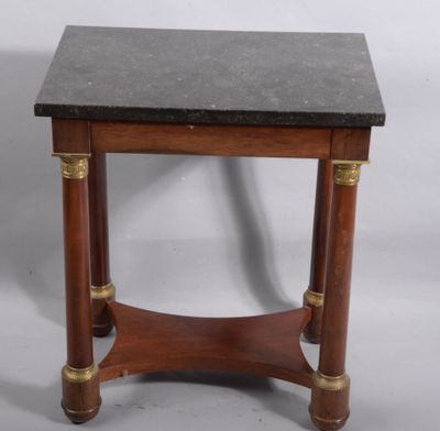 une vieille table en bois avec un plateau en marbre noir et des finitions en laiton