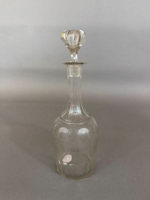 a clear glass bottle with a silver stopper sitting on top of a table
