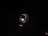 un gros plan d'un diamant posé sur une surface noire dans l'obscurité