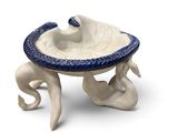 a white and blue bowl on a stand with an octopus on it