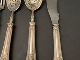 four silver spoons and a knife on a black table