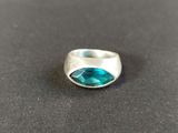 a close up of a silver ring with a blue stone