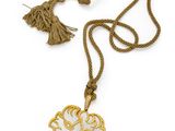 un collier blanc et doré orné d'un motif floral et d'un pompon