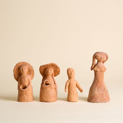trois figurines en argile représentant des femmes et un homme tenant un panier