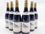 six bouteilles de vin sont alignées sur une surface blanche