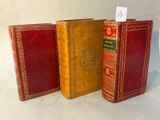 trois vieux livres sont alignés sur une surface blanche