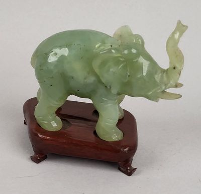 statue d'un éléphant posée sur un socle en bois, avec un fond blanc