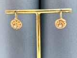 une paire de boucles d'oreilles en or sur un présentoir plaqué or