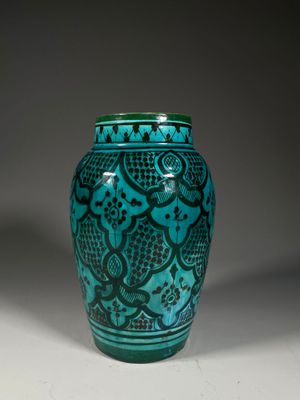 turquoise vase with a black design on the outside of it