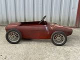 an old toy car that is rusted and sitting on the ground