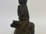 wooden figurine of a man sitting on a bear holding a book