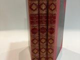 three red books sitting on top of each other on a white surface