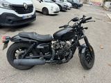 a black motorcycle parked in a parking lot next to a white van
