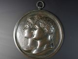 une image représentant une médaille d'argent sur laquelle figurent une femme et un homme