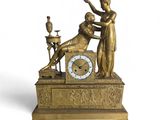 une horloge posée sur une table, sur laquelle se trouve une statue