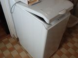 une petite machine à laver blanche dans un coin de la pièce
