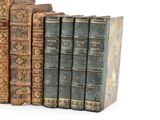several old books are stacked on top of each other on a white surface