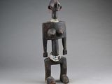 a wooden statue of a woman with a necklace on her neck