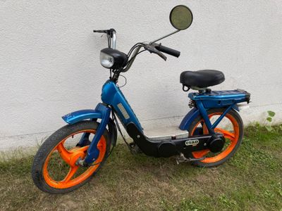 a blue and orange scooter parked in front of a white wall