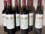 six bottles of red wine are lined up on a table
