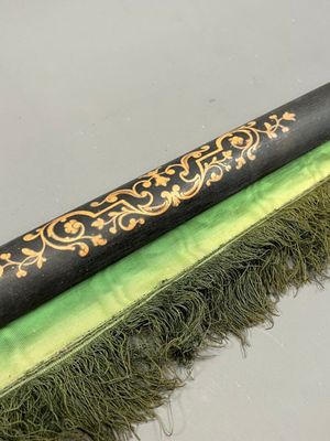 une image représentant un pinceau noir et vert orné d'une bordure dorée