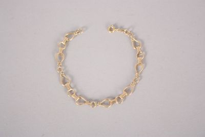 a close up of a gold chain bracelet on a white surface