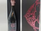 La bouteille de champagne se trouve dans une boîte noire ornée d'un motif rose.