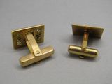 deux paires de boutons de manchette en or posés sur une surface grise