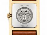 a close up of a watch on a white surface with a brown strap