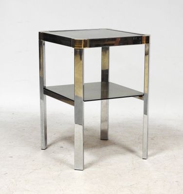 un gros plan d'une table d'appoint en métal et en verre posée sur une surface blanche